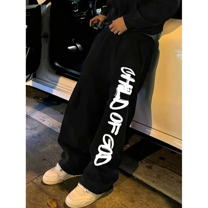 pantalones holgados streetwear para hombres en color negro con diseño de text o 'CHILD OF GOD' en la pierna.