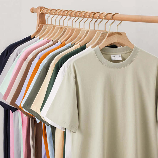 Xinjiang cotton heavyweight t-shirt en varios colores colgados en un perchero de madera.