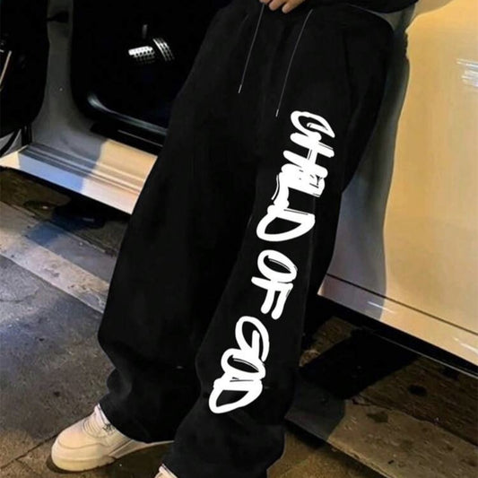 Hombre vistiendo ropa casual streetwear para hombres, pantalones negros con estampado 'Hijo de Dios'